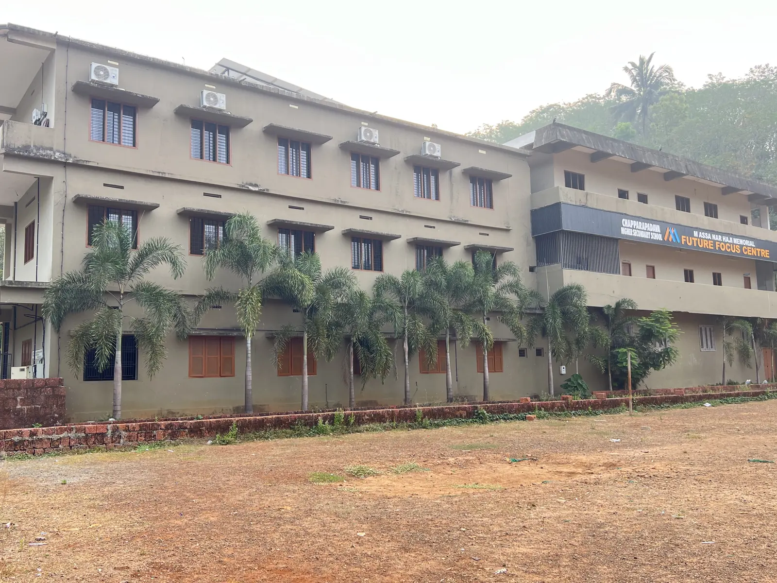 Main academic block of Chapparapadavu Higher Secondary School with palm trees and lawn